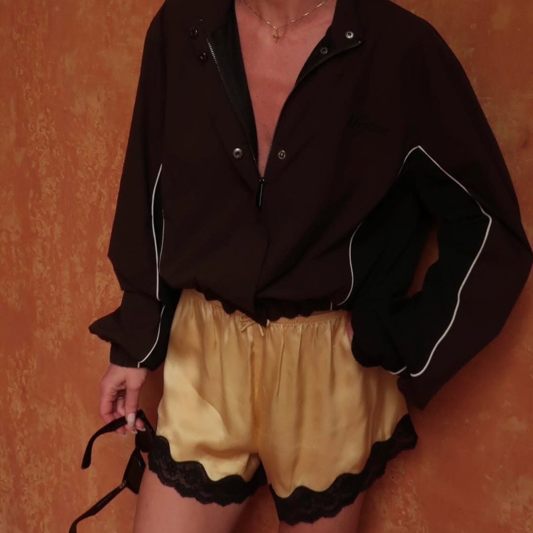 Ένα sporty καφέ αντιανεμικό τζάκετ συναντά ένα lingerie-inspired κίτρινο σορτς με μαύρη δαντέλα, αποδεικνύοντας ότι οι πιο ανατρεπτικοί συνδυασμοί είναι και οι πιο επιτυχημένοι.