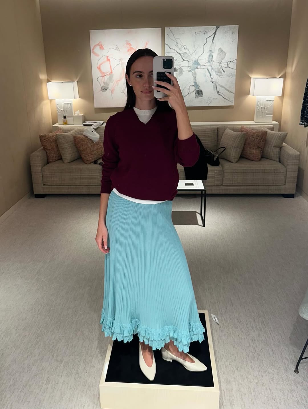High-fashion συνδυασμός με πλισέ μπλε μίντι φούστα και μπορντό τοπ, που αναδεικνύει πώς τα μίνιμαλ λευκά glove pumps με χαμηλό τακούνι αναβαθμίζουν ένα casual chic σύνολο.
