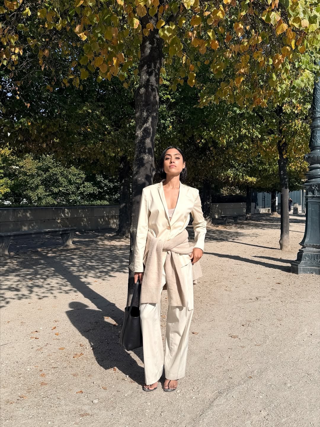 Γυναίκα με σικ street style look, φορώντας ιβουάρ κοστούμι, πουλόβερ και stretch thong πέδιλα.