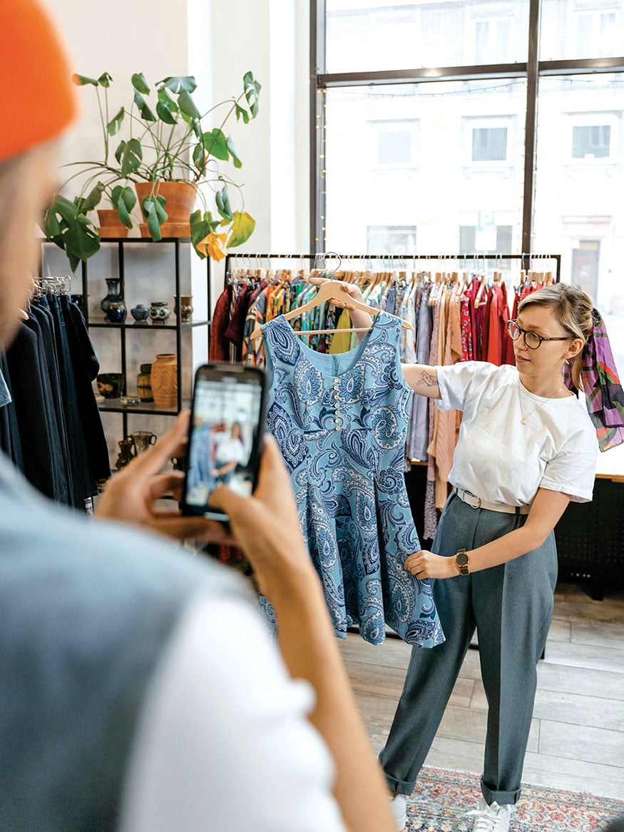 Γυναίκα που φωτογραφίζει vintage ρούχα- Vinted resale fashion trends